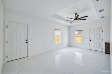 Unfurnished room featuring a raised ceiling, ceiling fan, and light marble finish flooring