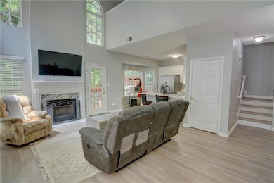 Living area featuring light wood finished floors, a fireplace, baseboards, a high ceiling, and stairway