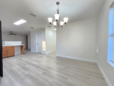 Unfurnished dining area featuring light wood-type flooring, a chandelier, and a ceiling fan