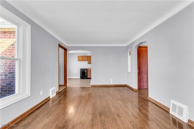 Unfurnished living room featuring visible vents, baseboards, arched walkways, and wood finished floors