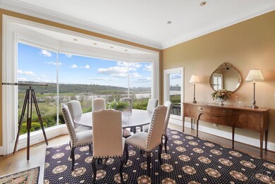 The bright, spacious and inviting great room boasts an 11' ceiling with recessed lighting, a wall of bowed floor-to-ceiling windows showcasing the picturesque river view, walkout access to the rear terrace, a gas fireplace and gleaming hardwood floors.