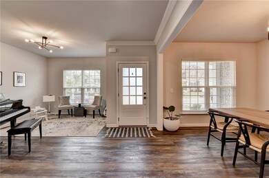 Entrance foyer with dark wood-style floors, a chandelier, baseboards, and crown molding