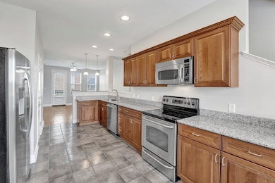 Kitchen with lots of cabinets, recessed lighting, stainless steel appliances, a sink, and a peninsula