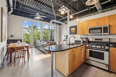 Kitchen featuring stainless steel appliances, a sink, a peninsula, concrete flooring, and open floor plan
