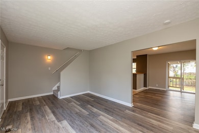 Living room featuring a textured ceiling and luxury vinyl plank floors.  View of Stairs upstairs and Dining Room