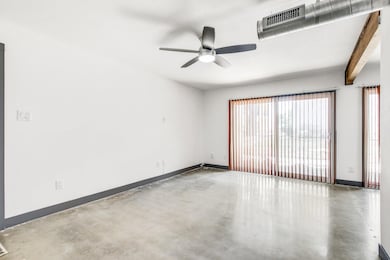 Empty room with finished concrete floors, ceiling fan, and beamed ceiling