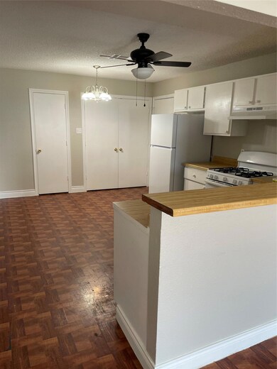 Kitchen with a textured ceiling, stove, a peninsula, white cabinetry, and a chandelier