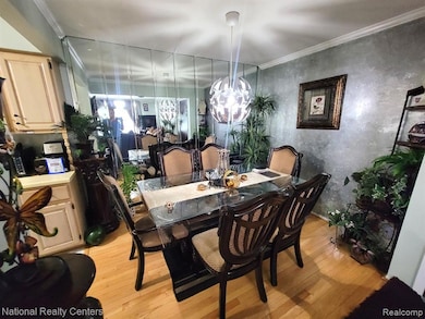 Dining area with light wood-style flooring, ornamental molding, and a chandelier
