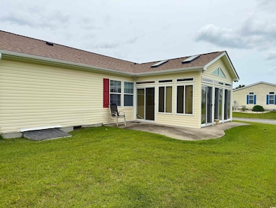 Rear view of house featuring a lawn, crawl space, a shingled roof, and a sunroom