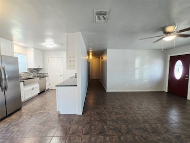 Kitchen with healthy amount of natural light, white cabinetry, stainless steel appliances, and backsplash