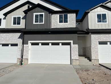 View of front facade featuring stone siding, board and batten siding, driveway, and an attached garage
