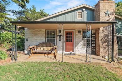 View of front of home with a porch, a chimney, a front lawn, and stone siding