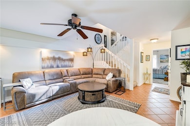 Living area featuring stairway, light tile patterned floors, and ceiling fan