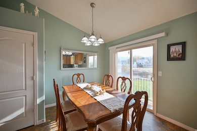 Dining space featuring a chandelier, vaulted ceiling, and dark stone finish flooring