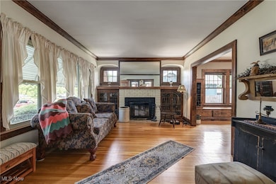 Living room featuring crown molding, light hardwood / wood-style flooring, and a brick fireplace