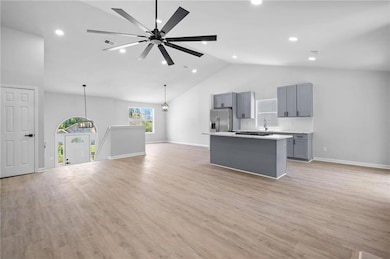 Kitchen with stainless steel fridge with ice dispenser, gray cabinetry, a center island, open floor plan, and high vaulted ceiling