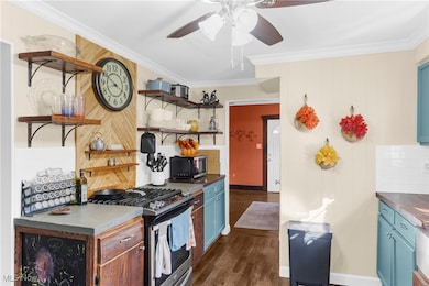 Kitchen featuring stainless steel appliances, open shelves, dark countertops, wood walls, and crown molding