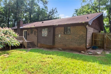 Back of house with a wooden deck, brick siding, and a chimney