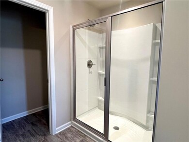 Full bathroom featuring a shower stall and baseboards