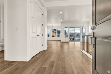 Hallway featuring light wood-type flooring and a notable chandelier