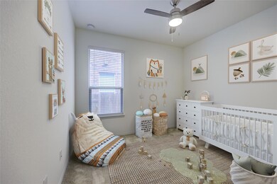 Bedroom featuring carpet, a crib, and ceiling fan