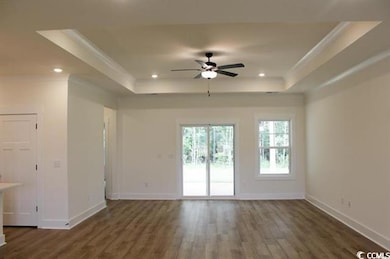 Unfurnished living room with a raised ceiling, dark wood-style flooring, recessed lighting, a ceiling fan, and crown molding