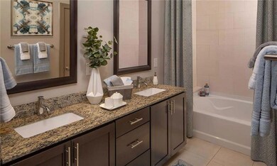 Bathroom featuring a tub, tile patterned floors, and dual bowl vanity