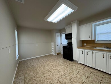 Kitchen with a sink, black appliances, light tile 