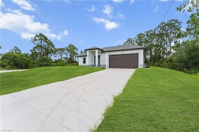 Prairie-style home with concrete driveway, a front lawn, stucco siding, and an attached garage