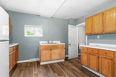 Kitchen with a sink, dark wood-style floors, light countertops, and fridge