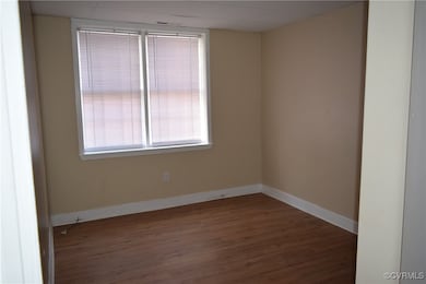 Unfurnished room with wood finished floors and bas