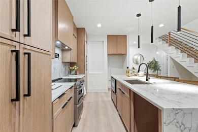 Kitchen with light stone counters, a sink, refrige