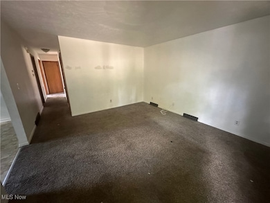 Empty room with dark colored carpet and baseboards