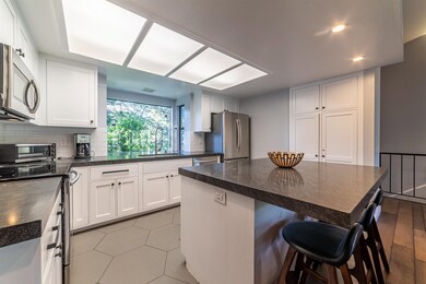Kitchen with appliances with stainless steel finishes, dark countertops, a kitchen breakfast bar, decorative backsplash, and white cabinets