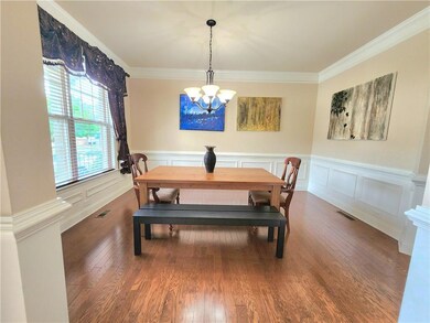Dining space with a chandelier, wood finished floors, a wainscoted wall, and ornamental molding