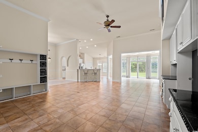 Unfurnished living room featuring ornamental molding, ceiling fan, light tile patterned floors, and a towering ceiling