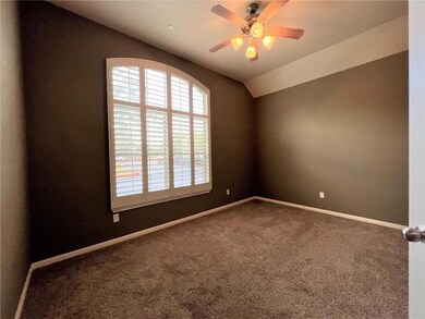 Carpeted empty room with a ceiling fan and vaulted ceiling