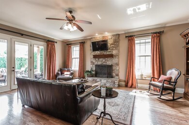 Living Room– 24x19– with Arched entry, hardwood floor, Stacked Stone Fireplace, Crown Molding, Recessed Lights, Ceiling Fan and Glass French Doors that lead to Covered Patio and Back Yard. 