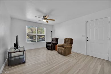Sitting room featuring light wood-style flooring and a ceiling fan