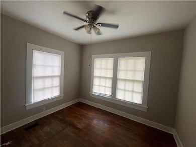 Spare room with a ceiling fan, dark wood-style floors, and baseboards