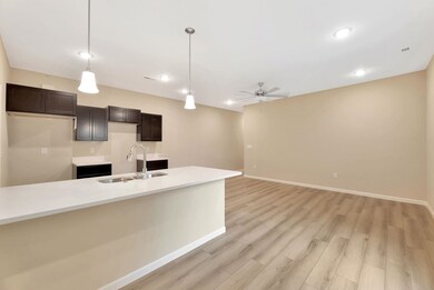 Kitchen featuring hanging light fixtures, light stone countertops, light wood-style floors, dark brown cabinetry, and ceiling fan