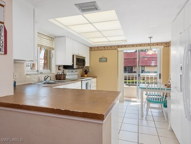 Kitchen with white cabinetry, visible vents, stain