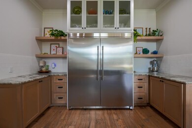 Kitchen featuring open shelves, tasteful backsplash, light stone counters, and ornamental molding