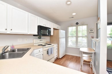 Kitchen with sink, white appliances, light hardwoo
