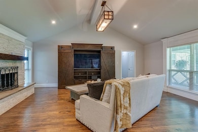 A Vaulted Ceiling Creates Spaciousness In The Family Room That's Accented By A Stone Fireplace,  Modern Lighting And Elegant Window Casing