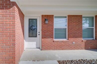 Doorway to property featuring brick siding and covered porch