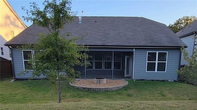 Back of house with a sunroom, a yard, an outdoor fire pit, and roof with shingles