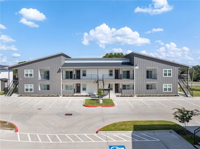 View of building exterior with stairs and uncovered parking