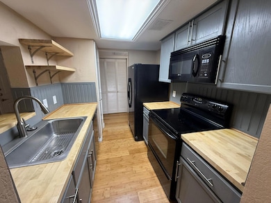 Kitchen featuring wood counters, sink, and black a