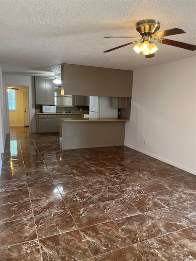 Kitchen with gray cabinetry, baseboards, fridge, 